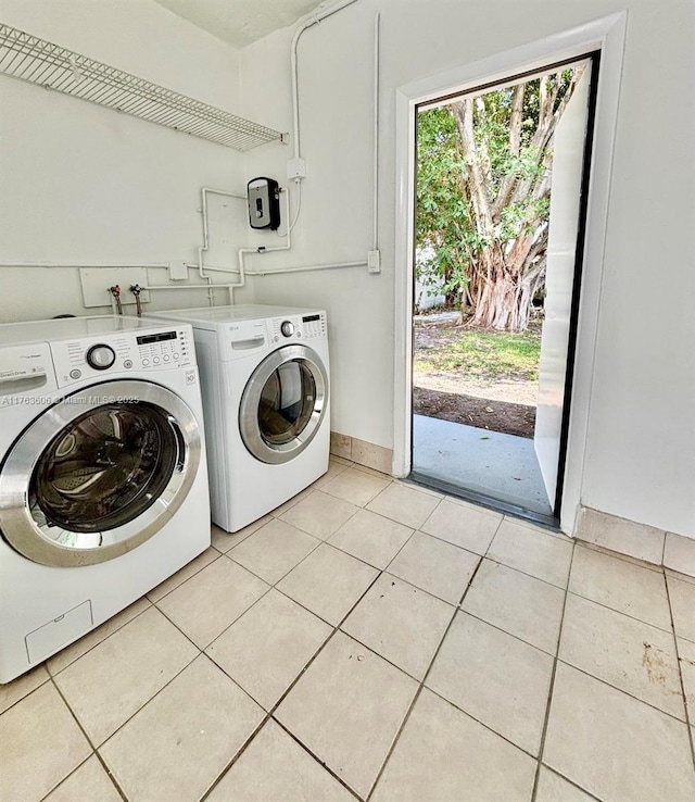 clothes washing area featuring laundry area, light tile patterned floors, baseboards, and washer and clothes dryer