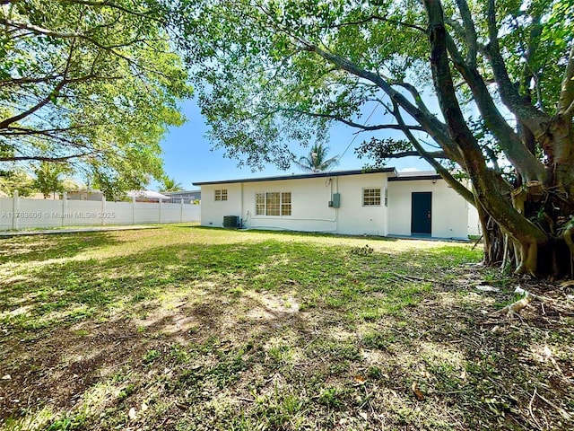 back of property with cooling unit, fence, a yard, and stucco siding