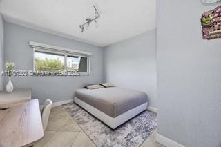 tiled bedroom featuring rail lighting and baseboards