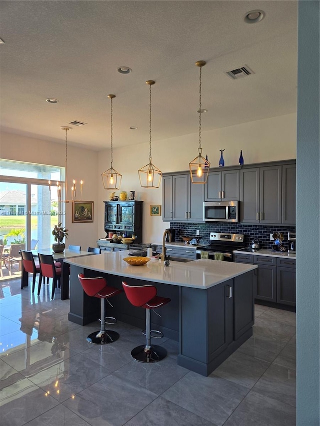 kitchen with decorative backsplash, light countertops, visible vents, and appliances with stainless steel finishes