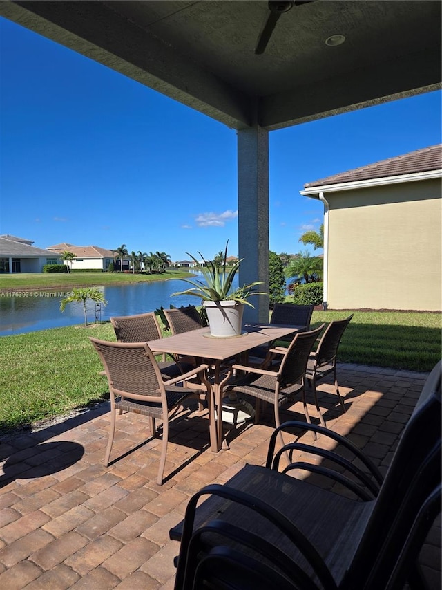 view of patio with outdoor dining area, a water view, and ceiling fan