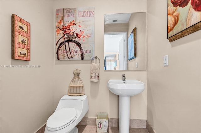 half bath with baseboards and toilet