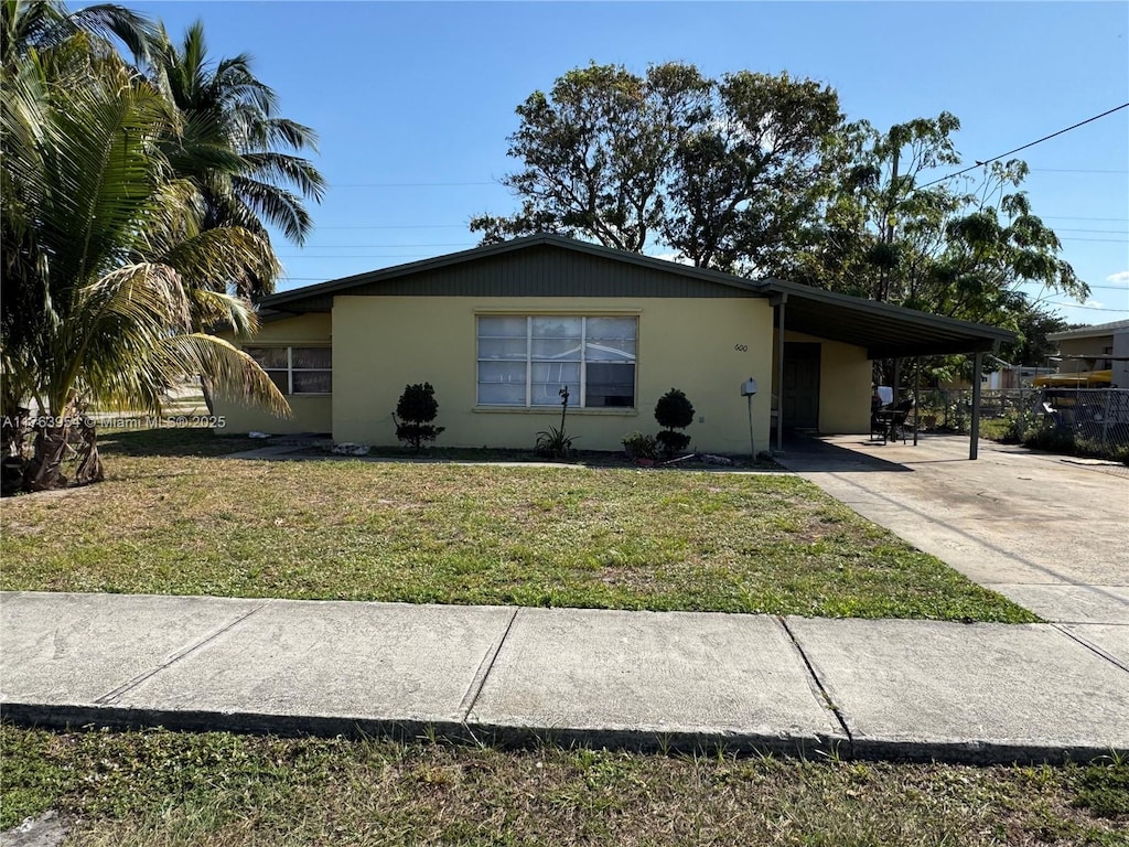 ranch-style house featuring stucco siding, a carport, concrete driveway, and a front lawn