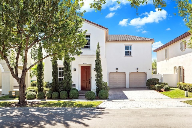 mediterranean / spanish-style house with a tile roof, a garage, driveway, and stucco siding