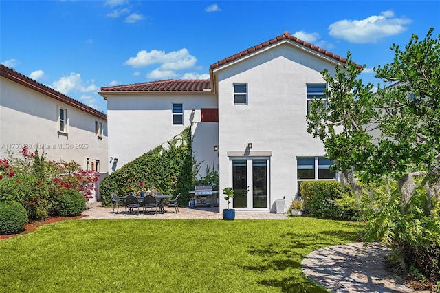 back of property featuring stucco siding, a tiled roof, a lawn, french doors, and a patio area