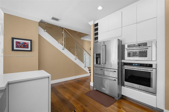 kitchen featuring visible vents, baseboards, appliances with stainless steel finishes, white cabinetry, and dark wood-style flooring