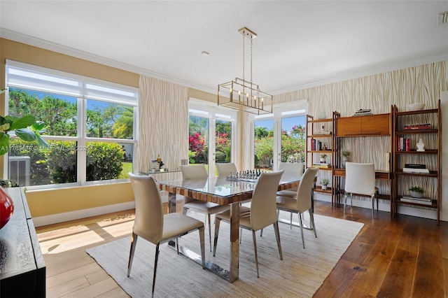 dining space featuring plenty of natural light, crown molding, an inviting chandelier, and wood-type flooring