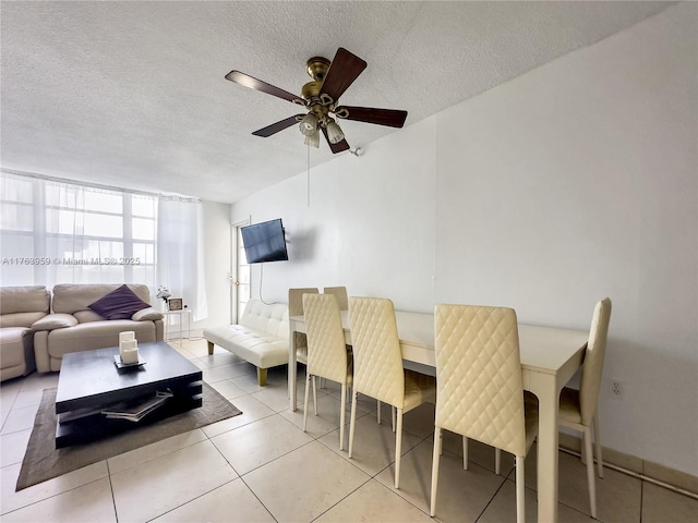 tiled dining space with a textured ceiling and a ceiling fan