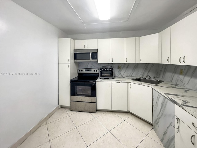 kitchen featuring a sink, stainless steel appliances, decorative backsplash, and light tile patterned floors