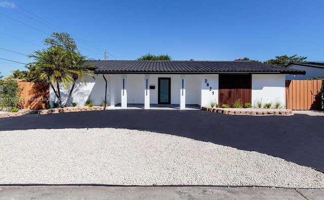 ranch-style home featuring stucco siding, fence, and a tiled roof