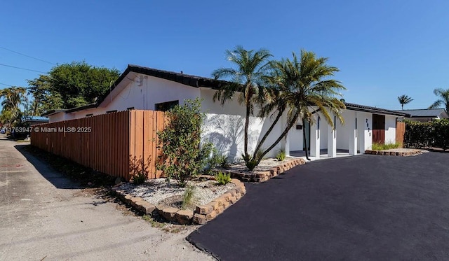 view of side of home with stucco siding and fence