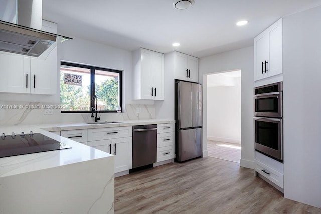 kitchen with a sink, ventilation hood, stainless steel appliances, white cabinets, and light stone countertops