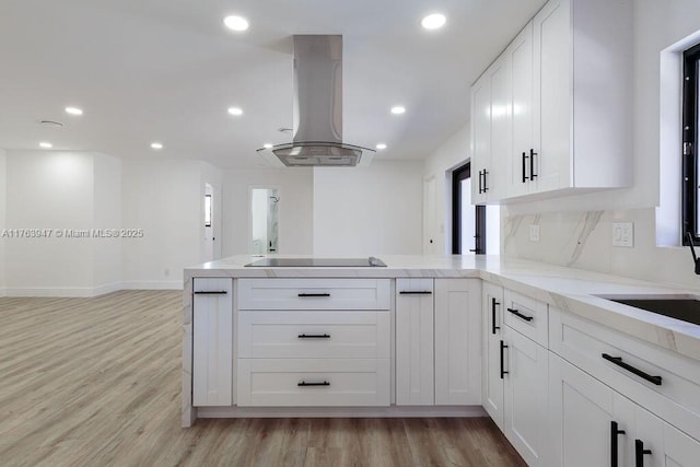 kitchen with a peninsula, black electric stovetop, island exhaust hood, and white cabinets