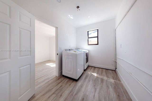 clothes washing area with washing machine and clothes dryer, laundry area, light wood finished floors, and baseboards