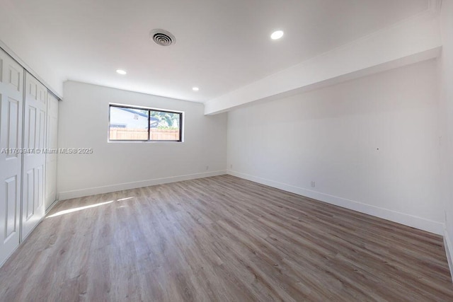 unfurnished bedroom with visible vents, baseboards, a closet, and wood finished floors