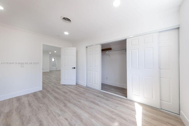 unfurnished bedroom with baseboards, visible vents, a closet, and light wood-type flooring