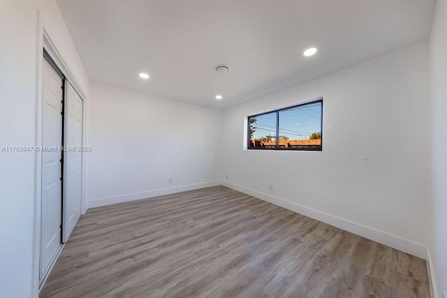 unfurnished bedroom featuring a closet, recessed lighting, light wood-type flooring, and baseboards