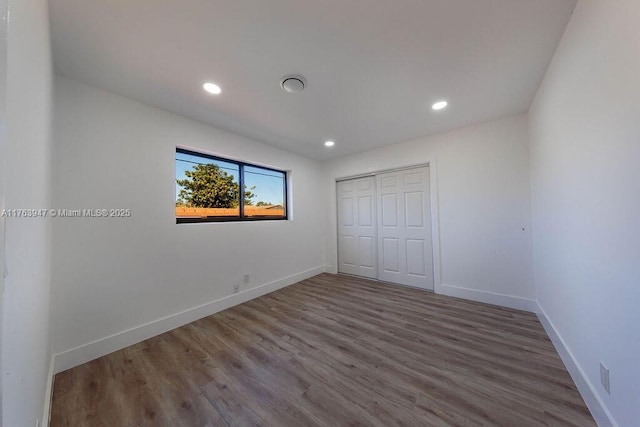 unfurnished bedroom featuring recessed lighting, a closet, baseboards, and wood finished floors