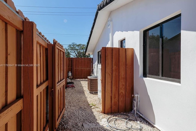 view of property exterior featuring a gate, stucco siding, cooling unit, and fence