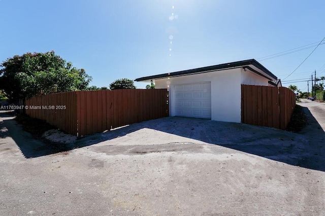 garage with fence and driveway