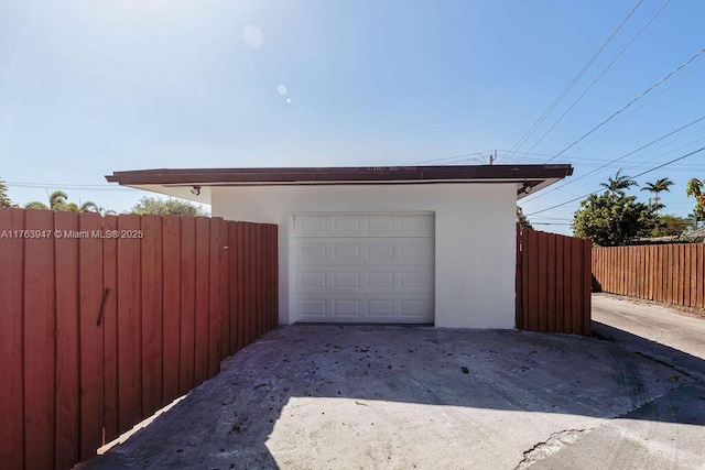 garage featuring concrete driveway and fence