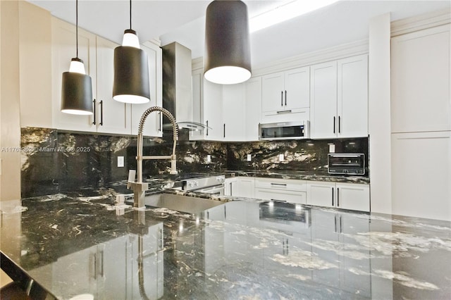 kitchen with a toaster, pendant lighting, stainless steel microwave, wall chimney exhaust hood, and backsplash