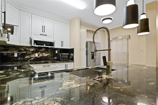 kitchen featuring tasteful backsplash, stainless steel microwave, white cabinets, and a toaster