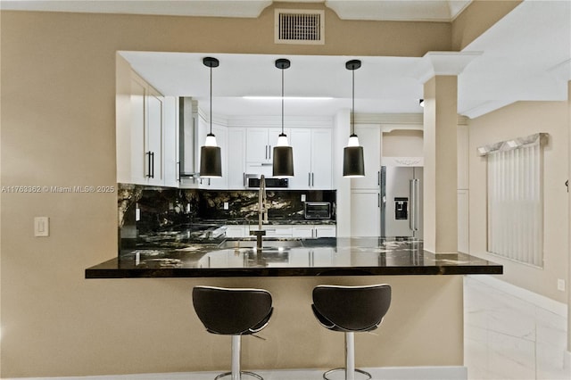kitchen featuring visible vents, stainless steel appliances, decorative light fixtures, a peninsula, and backsplash