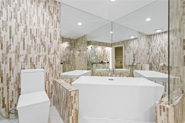 bathroom with recessed lighting, toilet, tile walls, and a soaking tub