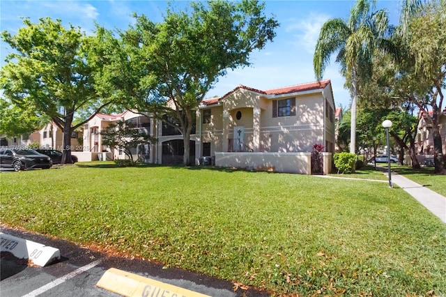 mediterranean / spanish home featuring stucco siding, a tiled roof, and a front lawn