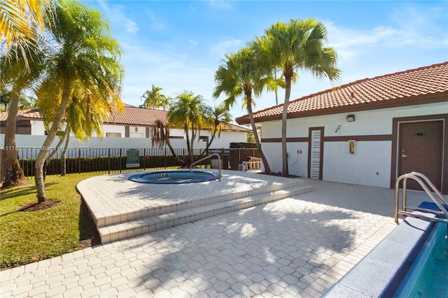 view of swimming pool with fence, a hot tub, and a patio area