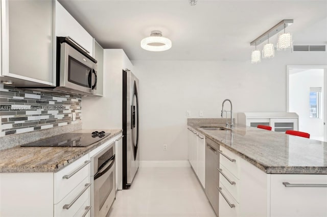 kitchen featuring visible vents, appliances with stainless steel finishes, tasteful backsplash, a sink, and a peninsula