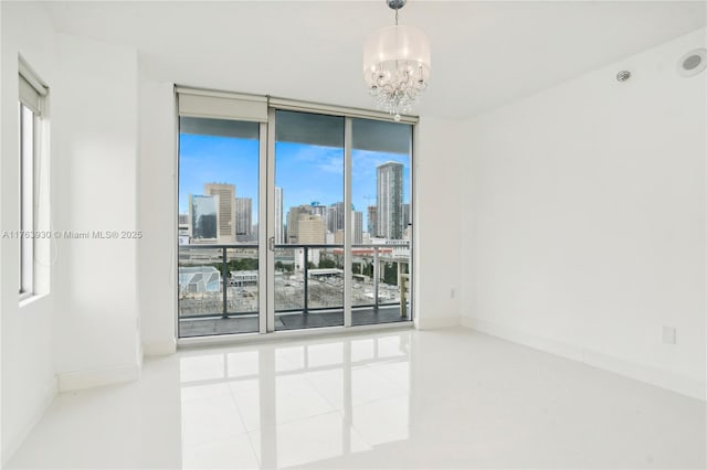 spare room with a healthy amount of sunlight, baseboards, floor to ceiling windows, a view of city, and a notable chandelier