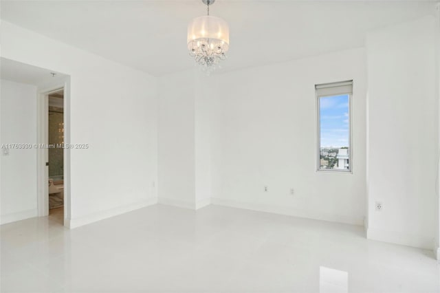 empty room with baseboards and a chandelier