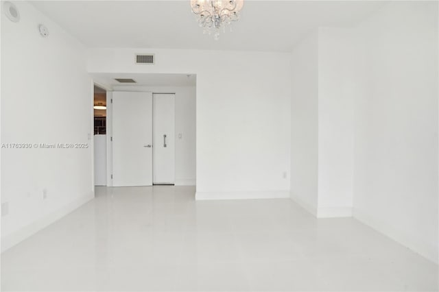 unfurnished room featuring a notable chandelier, visible vents, and baseboards