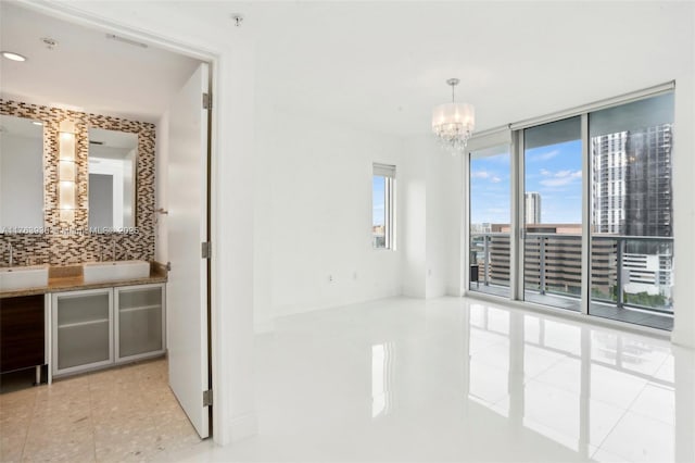 interior space with a sink, an inviting chandelier, a wall of windows, and tile patterned flooring