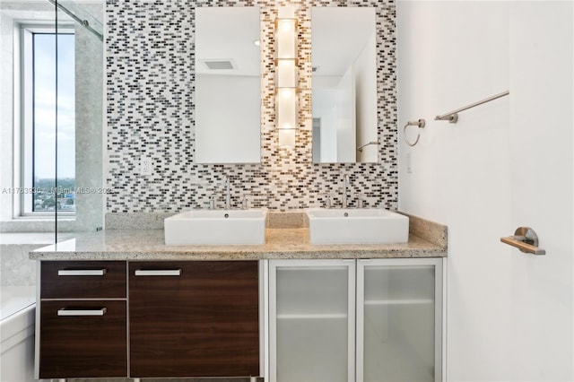 bathroom with double vanity, visible vents, backsplash, and a sink