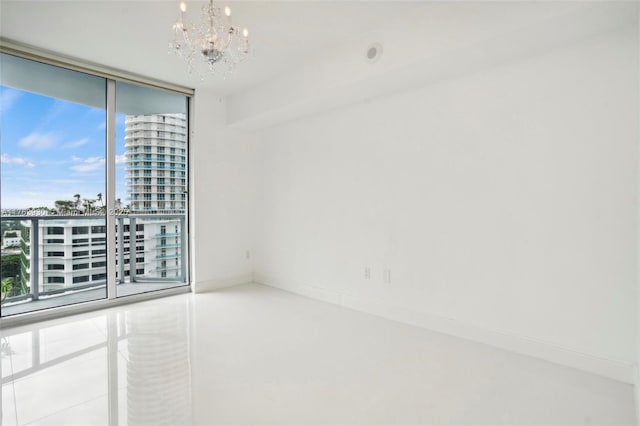 unfurnished room featuring a wall of windows, a city view, baseboards, and an inviting chandelier