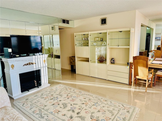 living room featuring light tile patterned floors, a fireplace, visible vents, and a textured ceiling