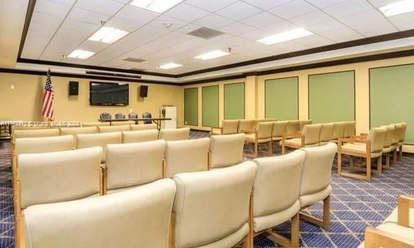 cinema with a tray ceiling, dark carpet, and ornamental molding