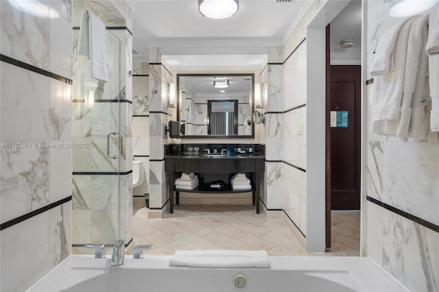 full bath with vanity, tile walls, toilet, and a marble finish shower