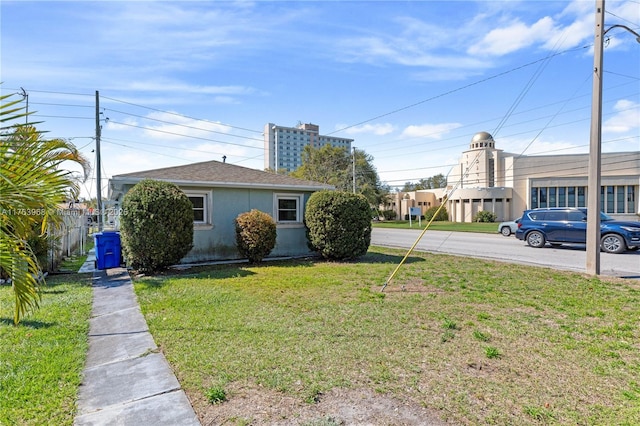 view of home's exterior with a lawn, fence, and stucco siding