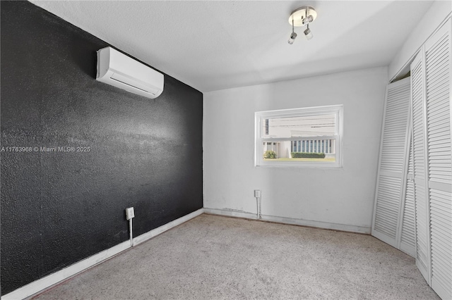 unfurnished bedroom with baseboards, a wall mounted air conditioner, a textured wall, a closet, and a textured ceiling