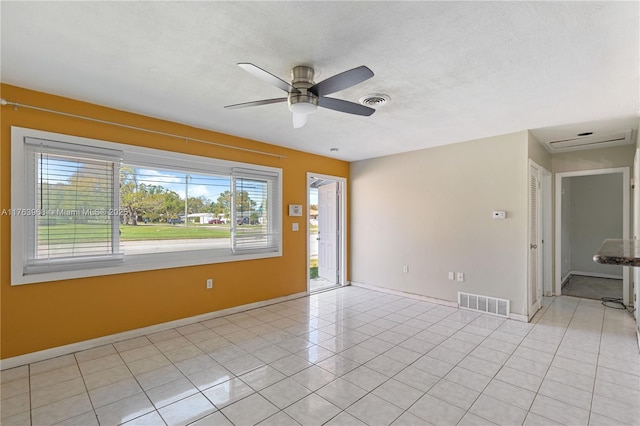 empty room featuring light tile patterned flooring, visible vents, and ceiling fan