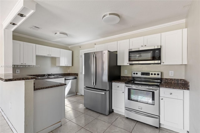 kitchen featuring a peninsula, white cabinets, ornamental molding, and stainless steel appliances