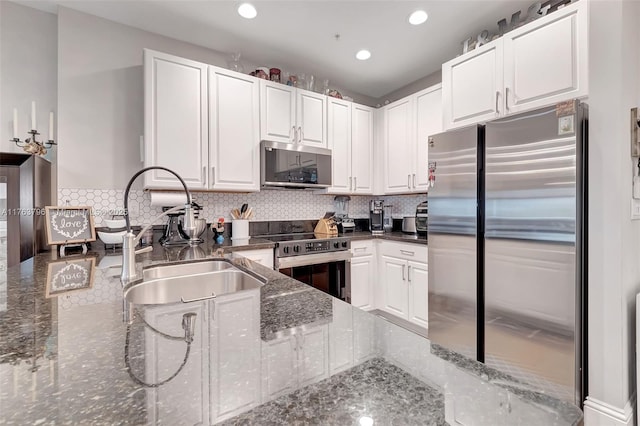 kitchen with backsplash, white cabinetry, stainless steel appliances, and a sink