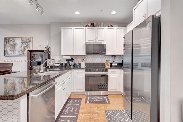 kitchen with a peninsula, tasteful backsplash, appliances with stainless steel finishes, and a sink