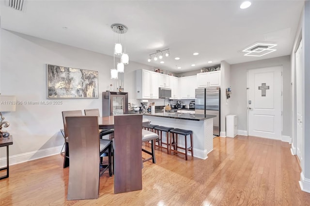 dining space with light wood-style flooring, baseboards, and visible vents