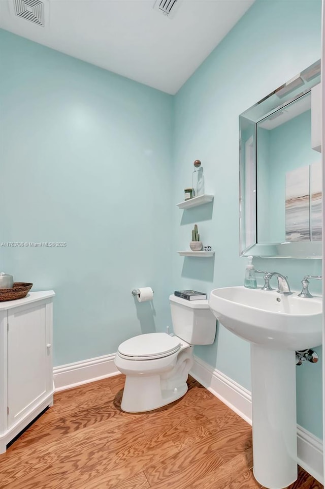 bathroom featuring wood finished floors, toilet, baseboards, and visible vents