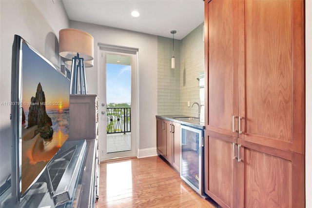 interior space featuring beverage cooler, brown cabinetry, light wood-style floors, and a sink